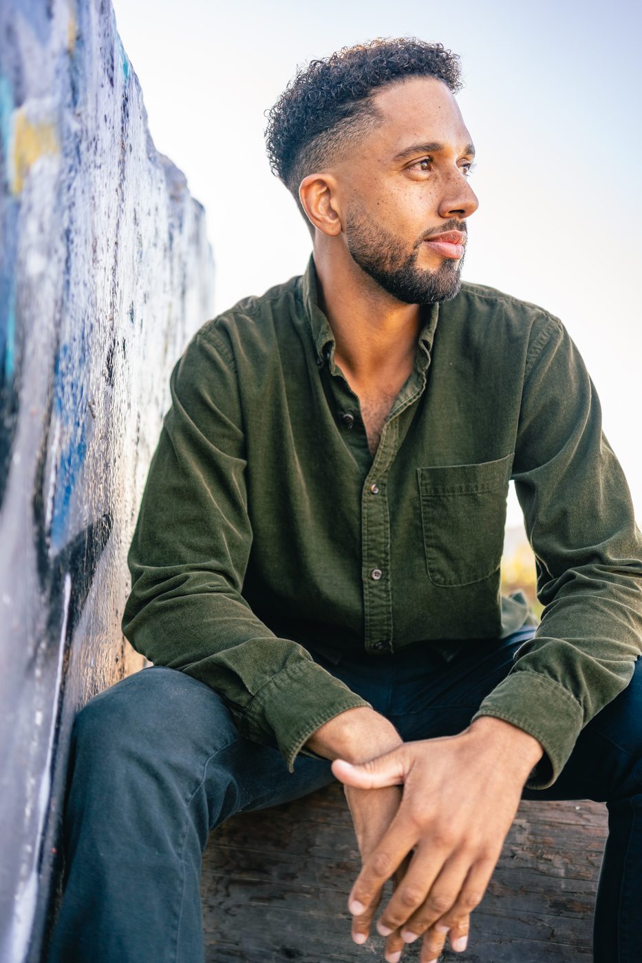 Nolan Krueger seated against a painted seawall, looking toward the water.