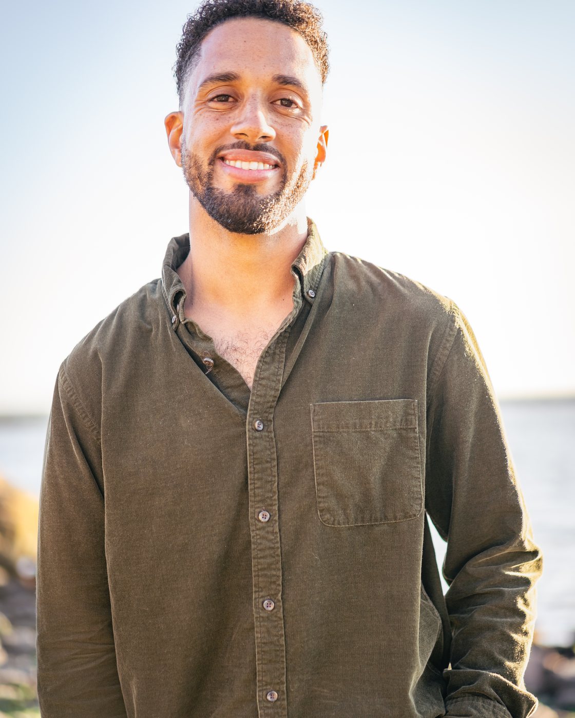 Nolan Krueger smiling at the coast in bright afternoon light.